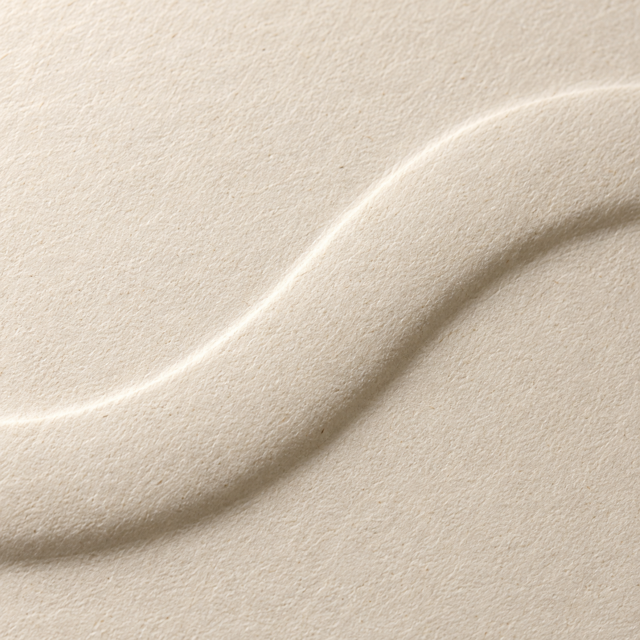 Close-up of textured ivory paper with a raised embossed mark