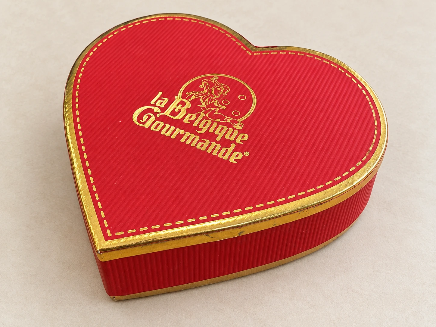 Red heart-shaped box with a gold foil logo and gold edge