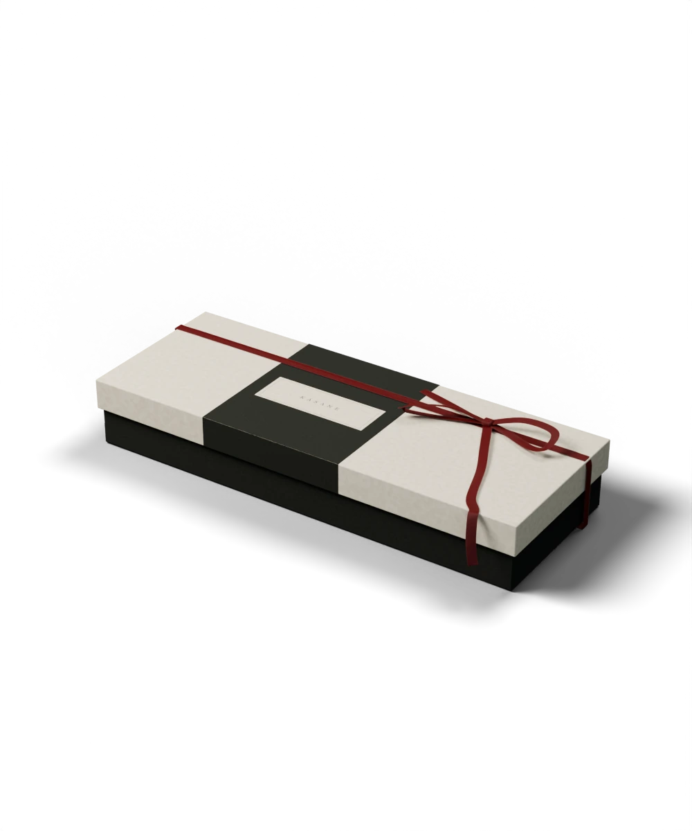 Illustrative KASANE gift packaging with a wrapped box, divider insert, tissue, seal, card and woven ribbon.