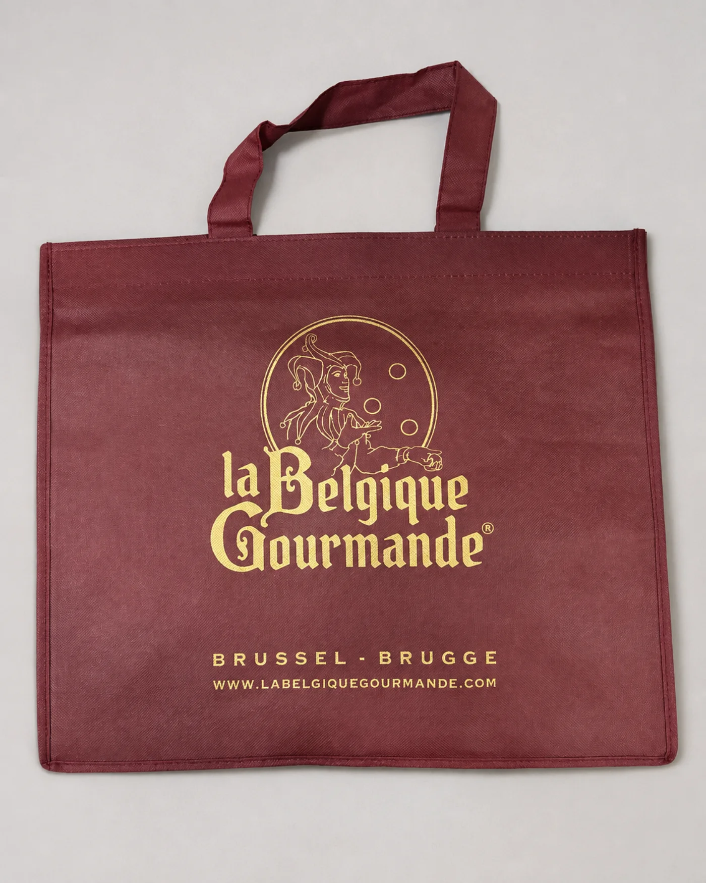 Burgundy reusable carrier bag with gold print and matching handles